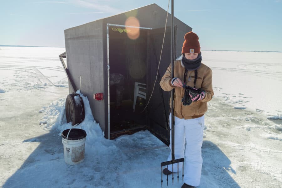 Woman standing outside shanty getting ready for sturgeon spearing