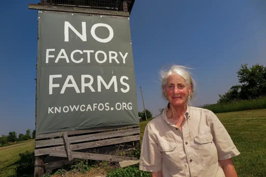 Woman in front of a sign that reads, "No factory farms."