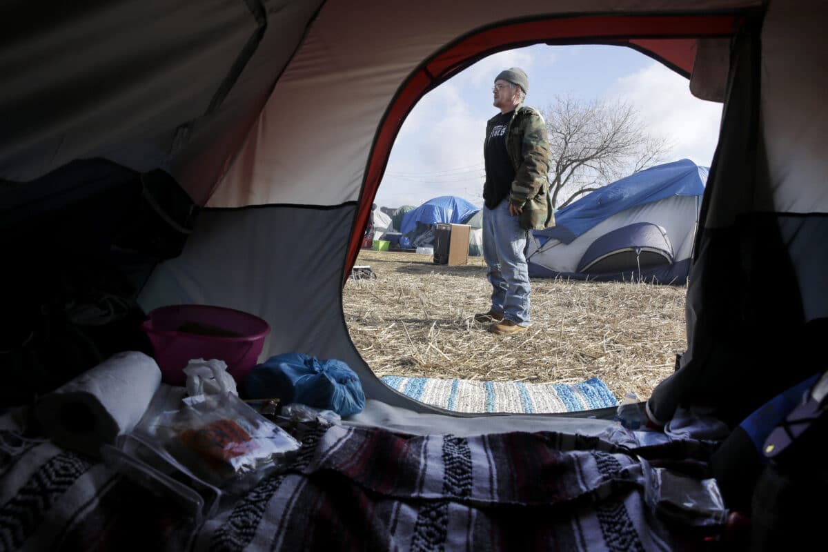 A homeless man stands outside of a tent in Missouri.